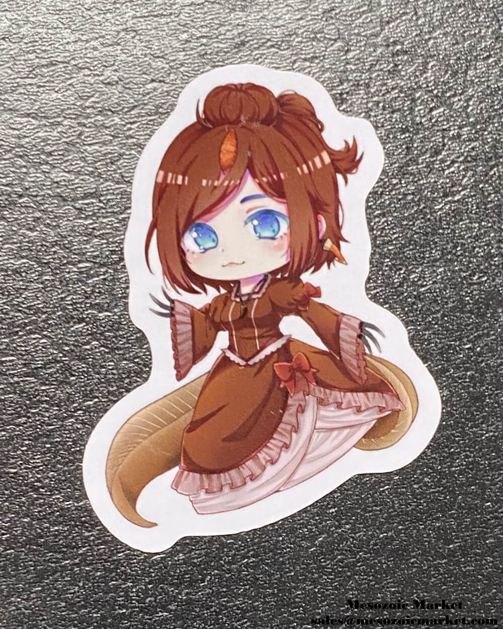 Type A variant of a vinyl sticker of our Spinosaurus anime girl mascot placed on a display box.